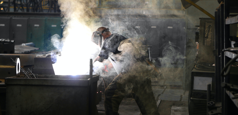 A man welding and surrounded by harmful weld smoke